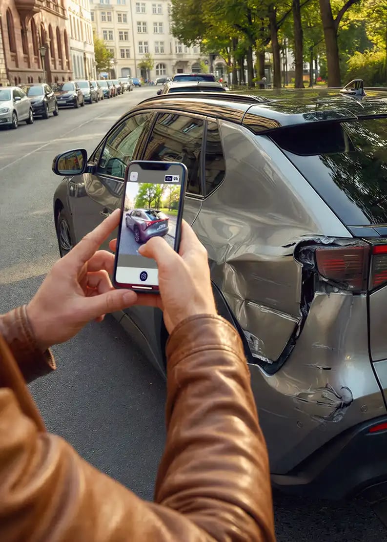 Person nimmt Schaden am Auto mit dem Handy auf.