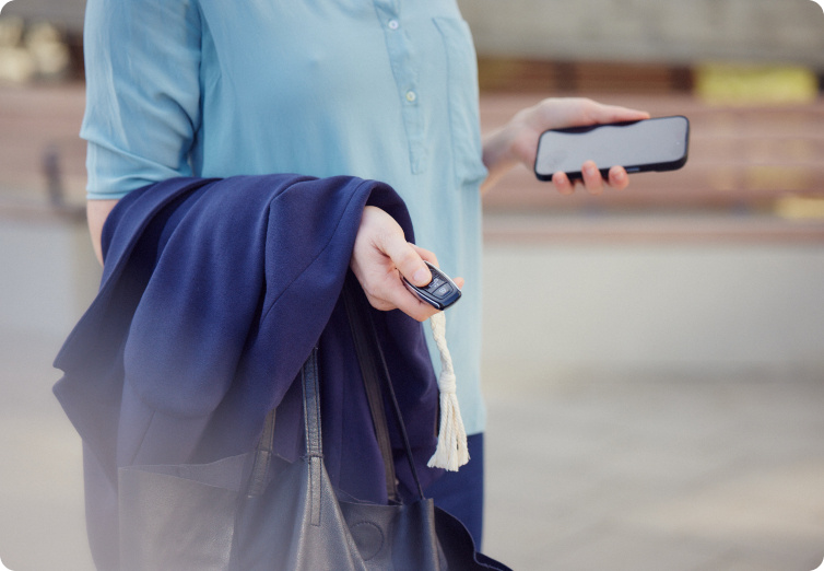 Autoschlüssel und Smartphone in den Händen einer Frau