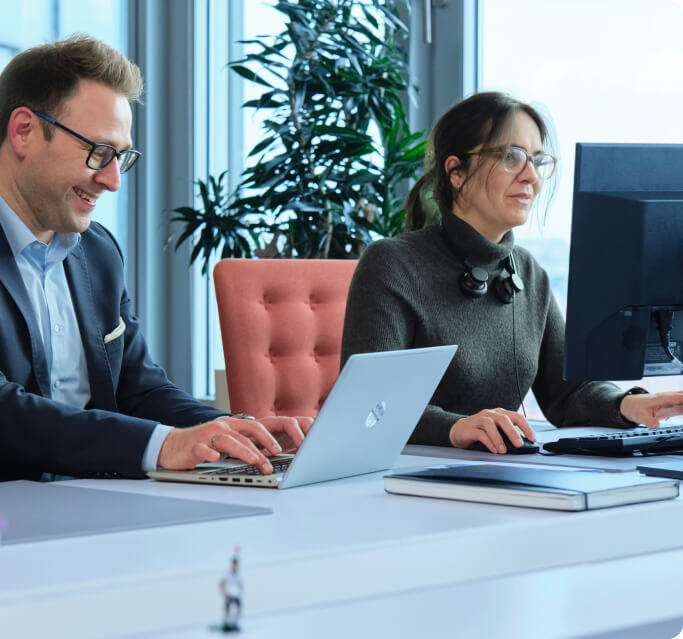 Zwei AFC Mitarbeitende an ihren Laptops