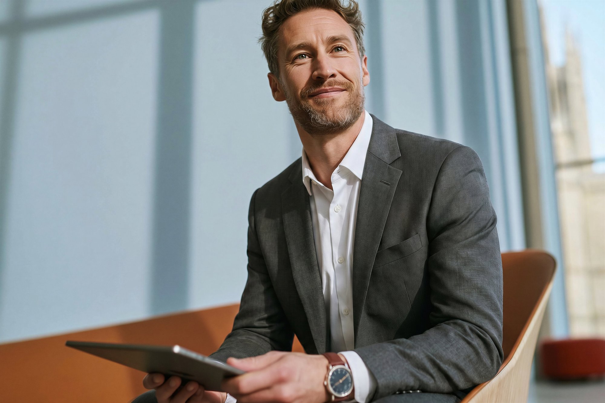 Mann sitzt im Bürostuhl mit Tablet in der Hand